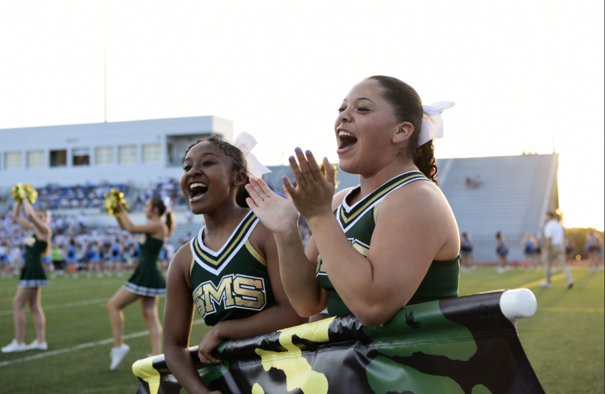 Laughing together, senior cheerleaders Eriah Knox and Aaliyah Bruce get excited during pregame cheer at the Sept. 20 football game. “[Senior year] has been really eventful and amazing, but all the games were so much fun and I just love having new memories with everyone,” Knox said. 